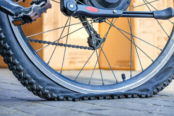 A punctured bicycle wheel on a blurred light sunny background.