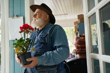 Senior man holding bunch of geranium in flower shop