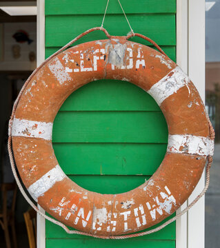 Old orange life preserver hanging on a green wall
