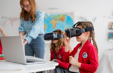 Happy schoolchildren wearing virtual reality goggles at school in computer science class