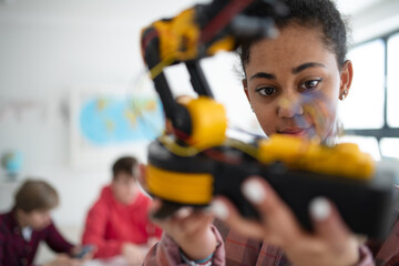 College student holding her robotic toy at robotics classroom at school.