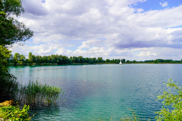Fototapeta na wymiar Ehrlichsee near Oberhausen-Rheinhausen. Bathing lake with surrounding landscape in summer. 