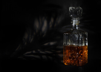 Glass vessel, a decanter with a light brown liquid poured in half closed with a glass stopper