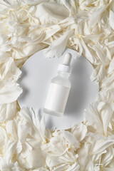 A jar of serum on the petals of a peony