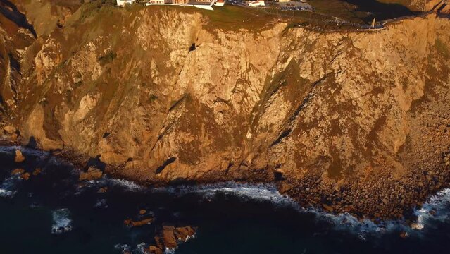 Wild impregnable rocky coastline of Portugal, Lisbon area. Aerial view at scenic huge cliffs with waving Atlantic ocean in the foot, breathtaking view of westernmost point of Europe - Cape Roca
