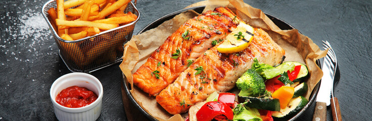 Salmon steak with vegetables on dark background.
