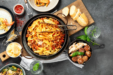 Assortment of Italian pasta with traditional sauces for dinner on dark background. Homemade food concept