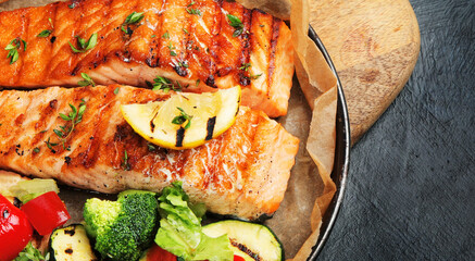 Salmon steak with vegetables on dark background.