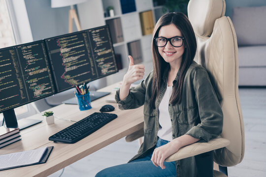 Portrait of beautiful cheerful skilled girl tech leader showing thumbup developing web project at workplace workstation indoors