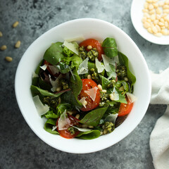 Healthy green salad with tomatoes, pesto and cheese