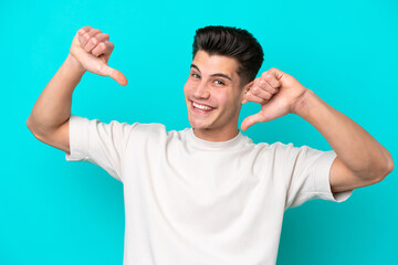 Fototapeta premium Young handsome caucasian man isolated on blue bakcground proud and self-satisfied