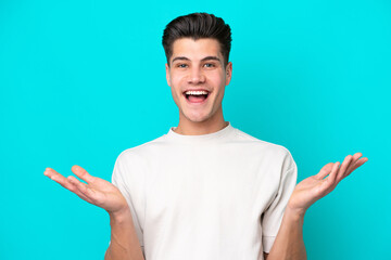 Young handsome caucasian man isolated on blue bakcground with shocked facial expression