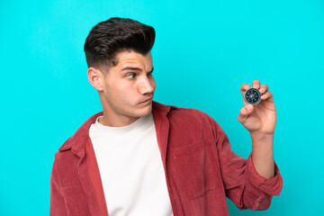 Young handsome caucasian man holding compass with sad expression