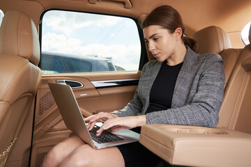 Businesswoman working on modern laptop in automobile