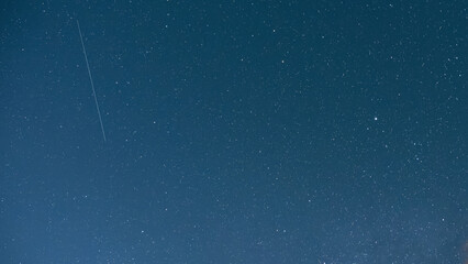 A blue starry sky with a trace of a passing meteorite. The night sky with stars. Background image.