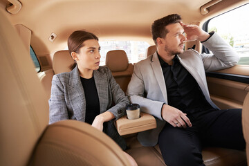 Man and woman sitting on back seats in automobile