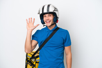 Young caucasian man with thermal backpack isolated on white background saluting with hand with happy expression