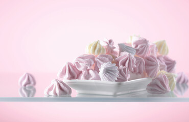 Fototapeta na wymiar Homemade colorful meringue on a pink background.