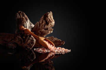 Pink salt with an old snag on a black reflective background.