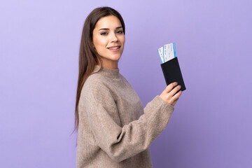 Young caucasian woman isolated on purple background happy in vacation with passport and plane tickets