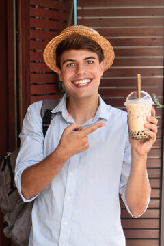 Happy man traveler drinking Asian boba milk tea