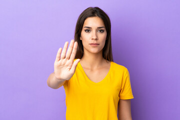 Fototapeta premium Young caucasian woman over isolated background making stop gesture