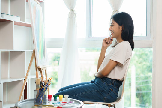 The art concept, Asian female artist sit front of canvas and thinking to create idea for artwork