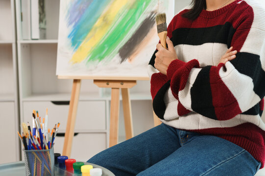 The art concept, Asian female artist sitting with her arms crossed and hold brush prepare for art