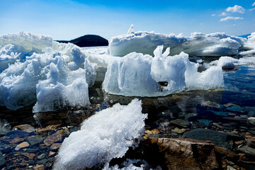 Sea coast with ice and stones. Seashore landscape in spring time.