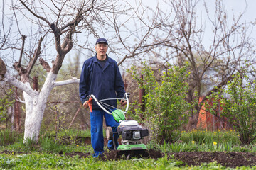 Farmer man plows the land with a cultivator preparing the soil for sowing