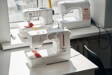 Digital sewing machines on desks in atelier