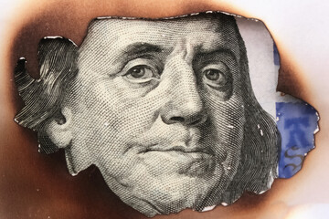 Obraz premium Burning US Dollar bill as a symbol of inflation and the global financial crisis
