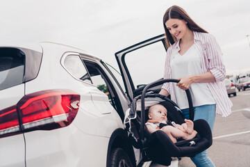 Photo of pretty adorable mommy son dressed casual clothes buckling up seatbelt seat putting inside auto transport