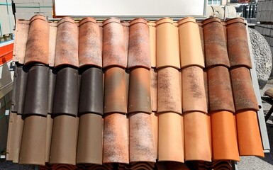 Samples of terracotta roof tiles on show by the building material store. Background and texture.