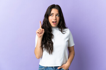 Young caucasian woman isolated on purple background thinking an idea pointing the finger up