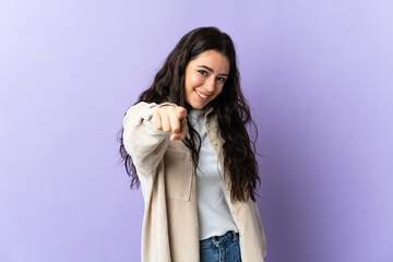 Young caucasian woman isolated on purple background pointing front with happy expression