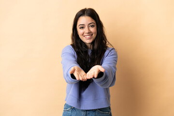 Young caucasian woman over isolated background holding copyspace imaginary on the palm to insert an...