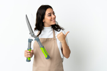 Young caucasian woman holding a plant isolated on white background pointing to the side to present...