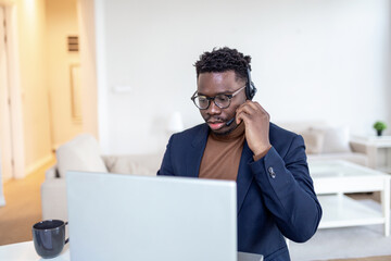Fototapeta na wymiar African American man wearing headphones reading good news in email, getting new job, promotion, using laptop