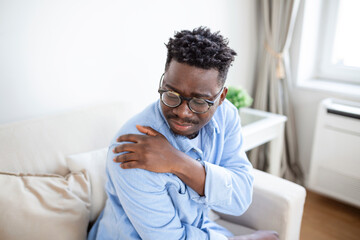 Tired man massaging stiff sore neck, tensed muscles fatigued from computer work in incorrect...