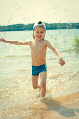 Little boy runs in the water, makes splashes