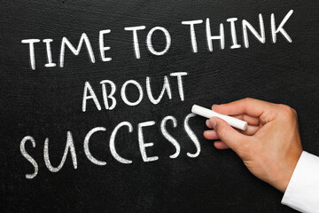 Fototapeta premium Motivational phrase written on black chalkboard. Hand with chalk.