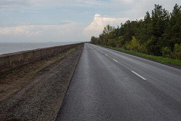 Road going far. Perfect road surface in the perspective of nature. Road between sea and forest. Beautiful road for travel