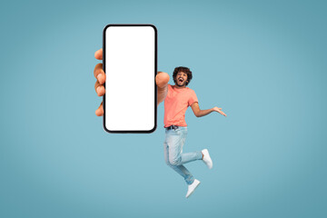Carefree eastern young man jumping with smartphone, mockup