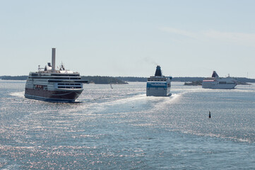 three ships in the Baltic sea. Blue water of the Stockholm fiord, blue sky with clouds