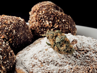 Vegan sugar-free cocoa truffles and medical cannabis bud on a slate plate.