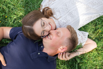 Summer fun of man and woman. Top view of young couple in love lying together on grass and smiling, honey moon, happy people