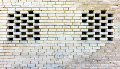 a brick wall of the auxiliary rooms with two air vents
