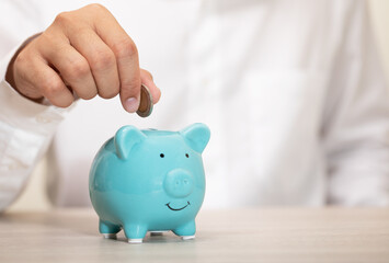 businessman hand putting coins on a blue piggy bank. saving money, Concept financial business investment, copy space