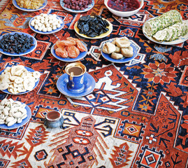 Eastern feast. Asian still life of dried fruits and nuts in plates on a carpet